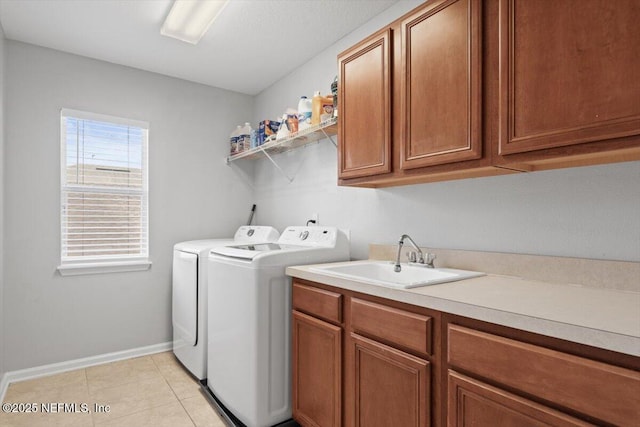 laundry area featuring sink, washer and clothes dryer, cabinets, and light tile patterned flooring