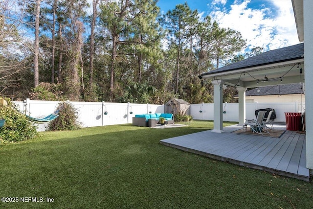 view of yard featuring a wooden deck, outdoor lounge area, and a shed