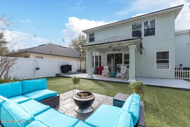 rear view of property with ceiling fan, a lawn, a patio area, and an outdoor living space with a fire pit