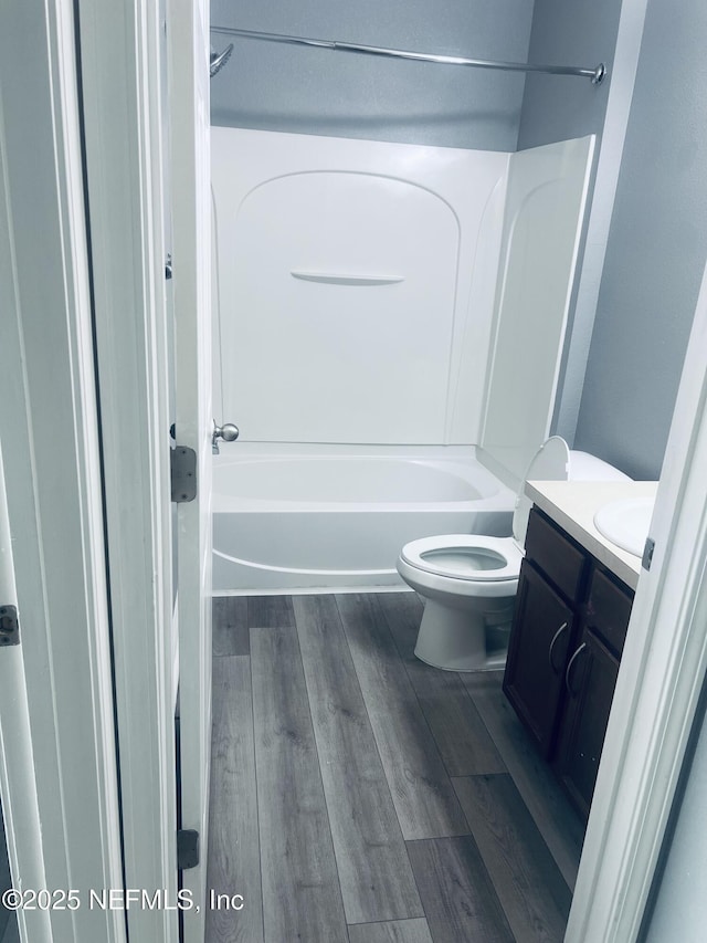 full bathroom featuring vanity, bathing tub / shower combination, hardwood / wood-style floors, and toilet