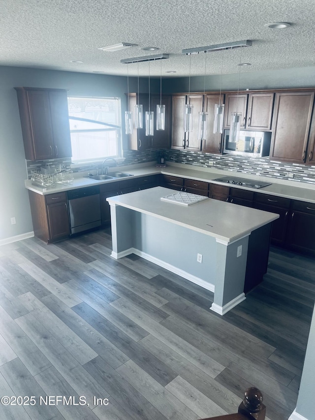 kitchen featuring pendant lighting, sink, hardwood / wood-style flooring, appliances with stainless steel finishes, and a kitchen island