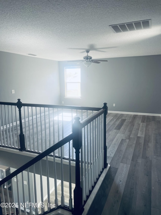 stairway featuring hardwood / wood-style flooring, ceiling fan, and a textured ceiling