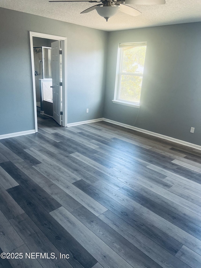 spare room featuring dark wood-type flooring, ceiling fan, and a textured ceiling