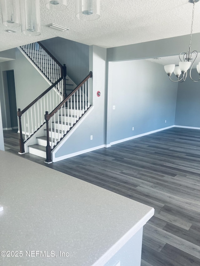 staircase featuring wood-type flooring, a notable chandelier, and a textured ceiling