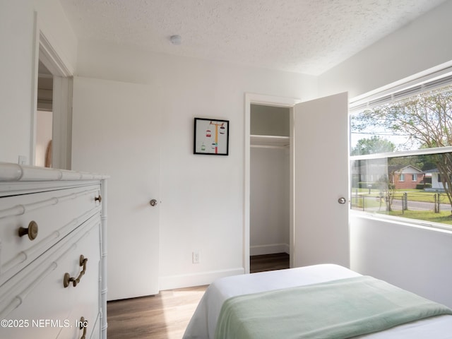 bedroom with wood-type flooring, a textured ceiling, and a closet