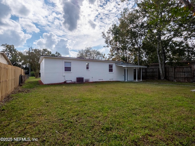 rear view of property with a lawn and central air condition unit