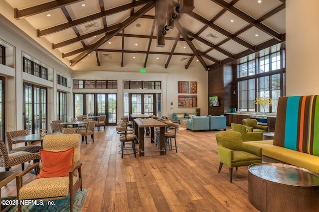 dining area with hardwood / wood-style floors, beam ceiling, and a high ceiling