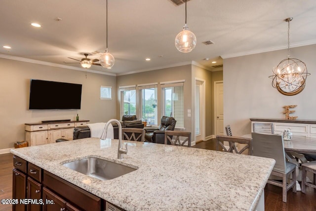 kitchen featuring sink, hanging light fixtures, crown molding, light stone countertops, and dark wood-type flooring