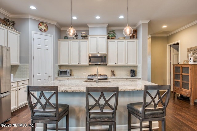 kitchen featuring pendant lighting, light stone counters, a center island with sink, and appliances with stainless steel finishes