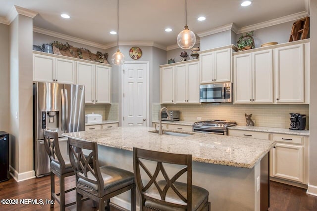 kitchen with stainless steel appliances, pendant lighting, a center island with sink, and a kitchen bar