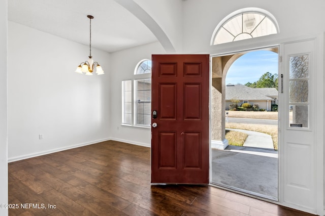 foyer with dark wood-type flooring and a notable chandelier