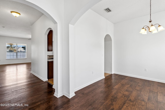 unfurnished room featuring dark hardwood / wood-style floors and a notable chandelier