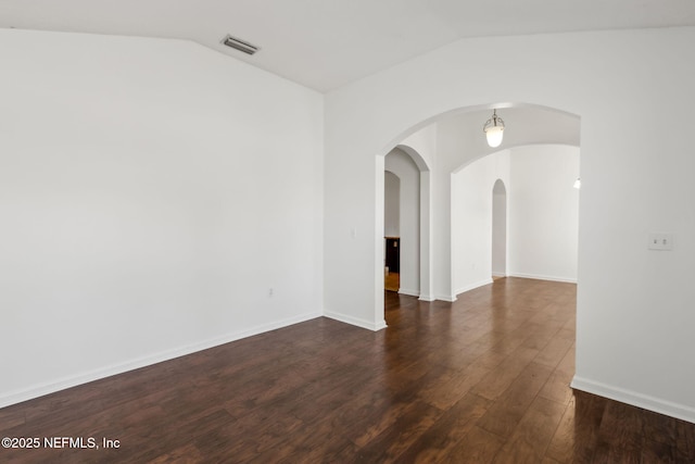 empty room featuring vaulted ceiling and dark hardwood / wood-style floors