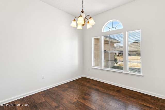 unfurnished room featuring dark hardwood / wood-style floors and an inviting chandelier