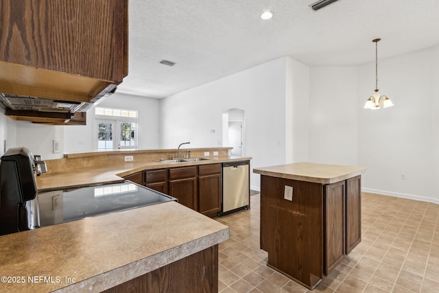 kitchen with sink, a textured ceiling, a kitchen island, pendant lighting, and stainless steel appliances