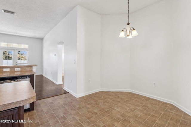 unfurnished dining area with a notable chandelier and a textured ceiling