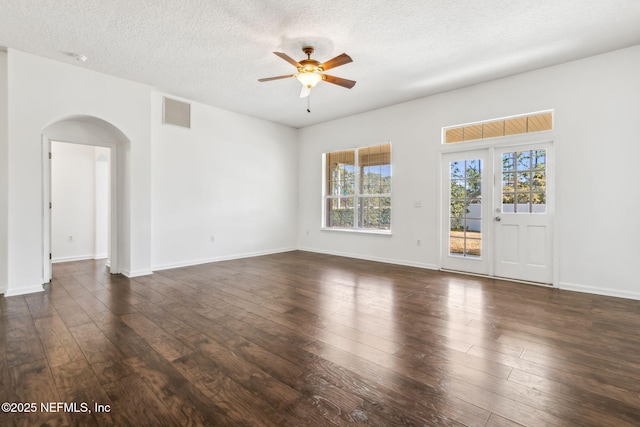 empty room with dark wood-type flooring, ceiling fan, and a healthy amount of sunlight