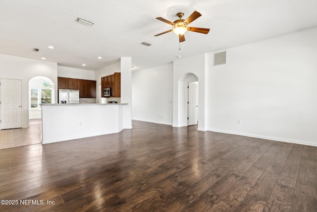 unfurnished living room with ceiling fan, a textured ceiling, and dark hardwood / wood-style flooring