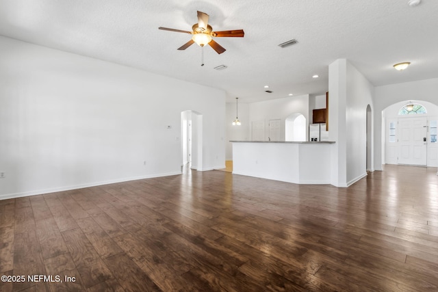 unfurnished living room with dark wood-type flooring, ceiling fan, and a textured ceiling