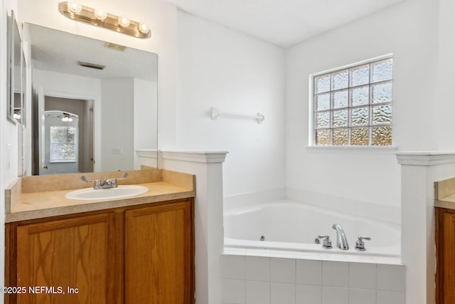 bathroom featuring vanity and tiled bath