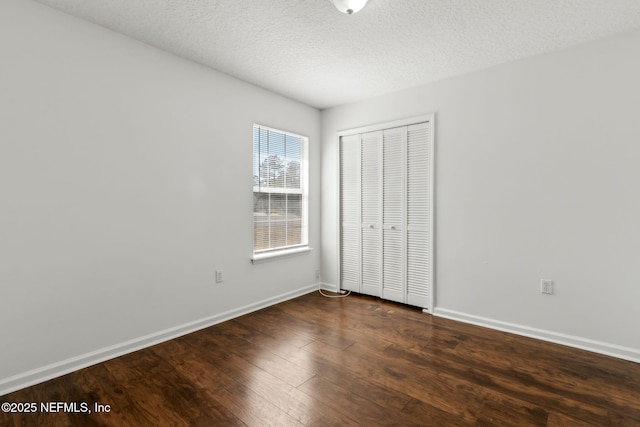 unfurnished bedroom with dark wood-type flooring, a textured ceiling, and a closet