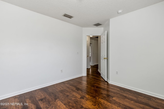 spare room with dark hardwood / wood-style floors and a textured ceiling