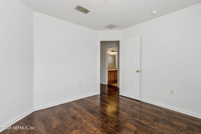 spare room with dark hardwood / wood-style floors and a textured ceiling