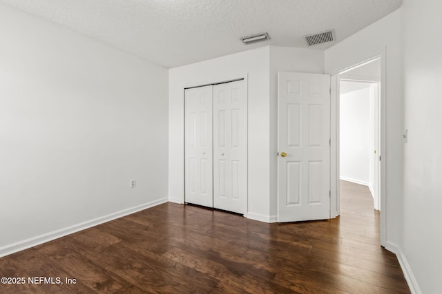 unfurnished bedroom with a closet, dark hardwood / wood-style flooring, and a textured ceiling