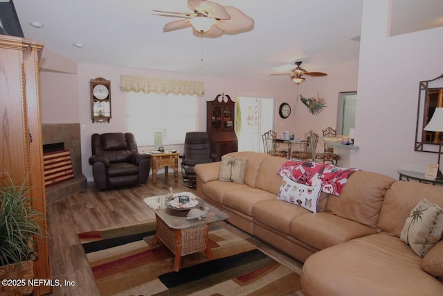 living room featuring a tiled fireplace, hardwood / wood-style flooring, and ceiling fan