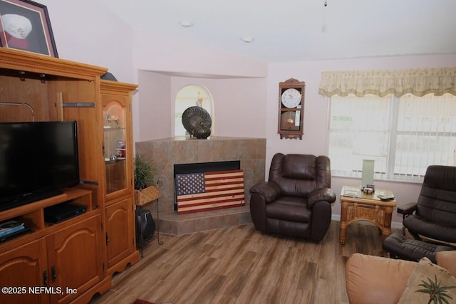 living room with a tiled fireplace and hardwood / wood-style floors