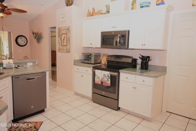 kitchen featuring light tile patterned flooring, lofted ceiling, ceiling fan, stainless steel appliances, and white cabinets