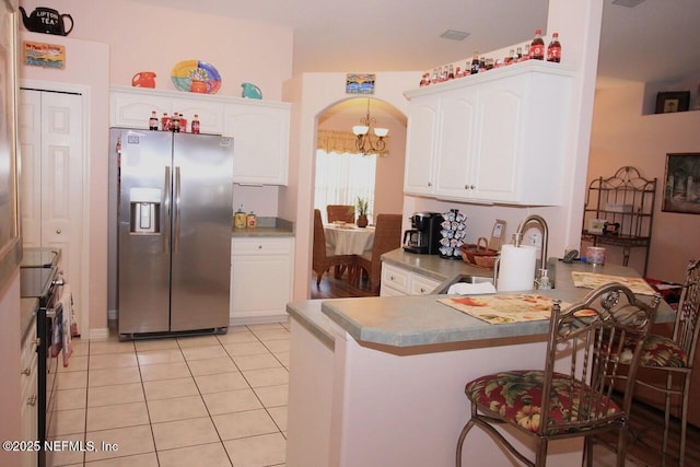 kitchen featuring sink, light tile patterned floors, white cabinetry, stainless steel refrigerator with ice dispenser, and kitchen peninsula