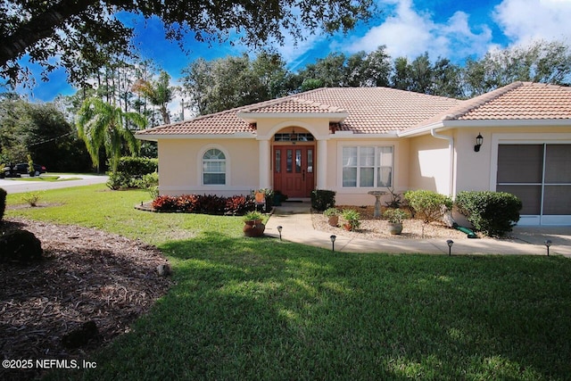 mediterranean / spanish-style house featuring a front lawn and french doors