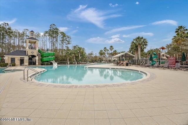 view of pool featuring a patio area, a playground, and a water slide