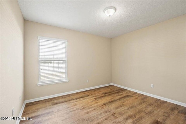 unfurnished room featuring light hardwood / wood-style flooring and a textured ceiling