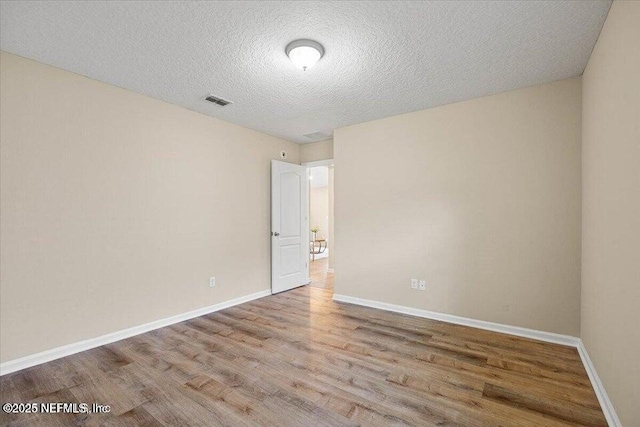 empty room featuring a textured ceiling and light wood-type flooring