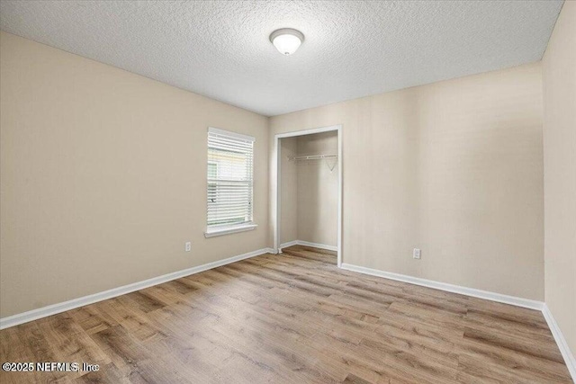 unfurnished bedroom with a textured ceiling, light hardwood / wood-style floors, and a closet