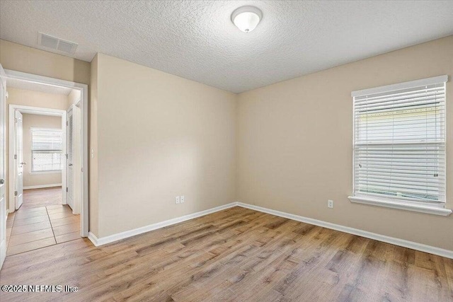 unfurnished room with light hardwood / wood-style flooring and a textured ceiling