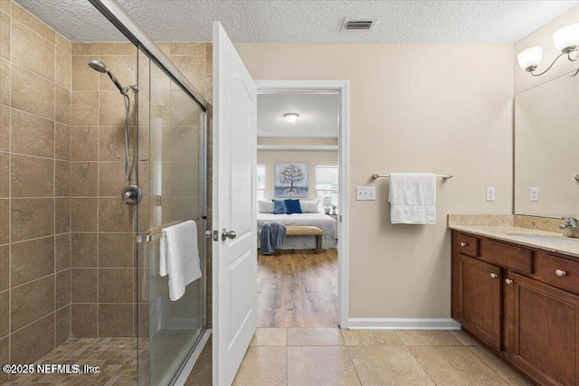 bathroom with walk in shower, tile patterned floors, vanity, and a textured ceiling