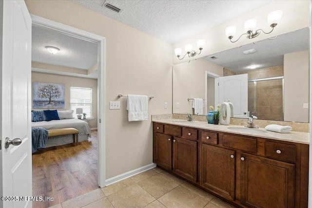 bathroom with vanity, tile patterned floors, an enclosed shower, and a textured ceiling