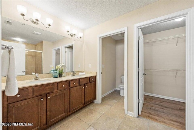 bathroom with vanity, a textured ceiling, tile patterned floors, toilet, and walk in shower