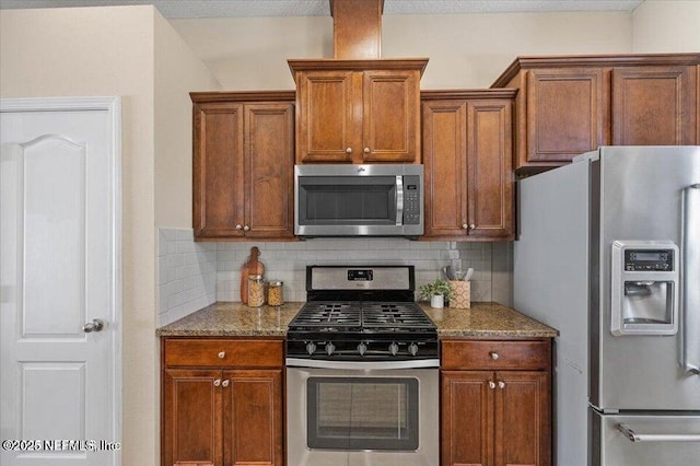 kitchen featuring decorative backsplash, stone counters, and appliances with stainless steel finishes