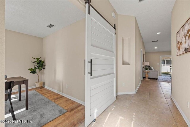 corridor with a barn door and a textured ceiling