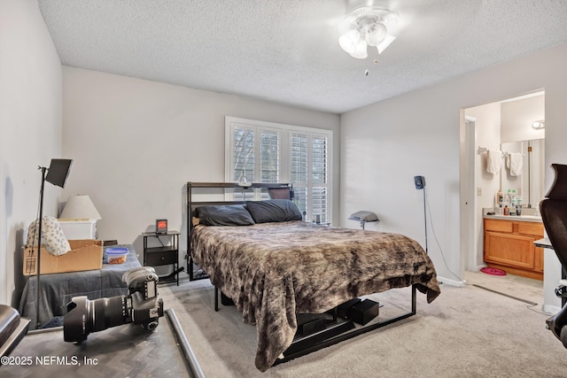 carpeted bedroom with ceiling fan, ensuite bathroom, and a textured ceiling