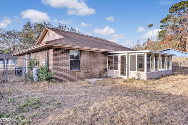 back of property with central AC unit and a sunroom