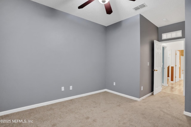 unfurnished room with ceiling fan, light colored carpet, and a textured ceiling