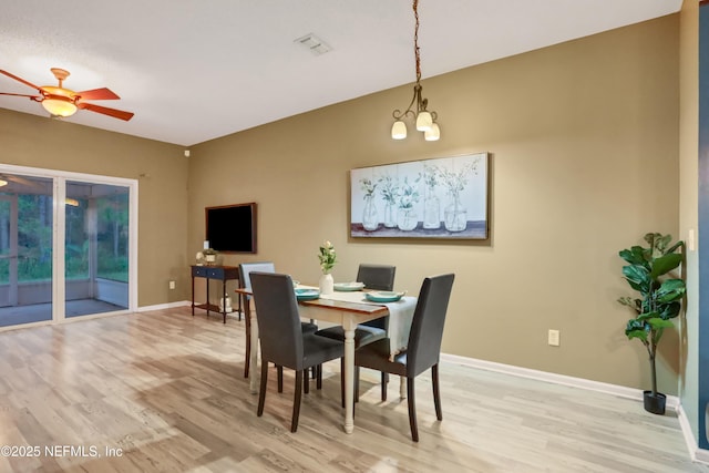 dining space with ceiling fan with notable chandelier and light hardwood / wood-style floors