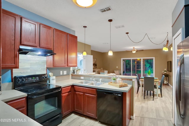 kitchen with sink, decorative light fixtures, light wood-type flooring, kitchen peninsula, and black appliances