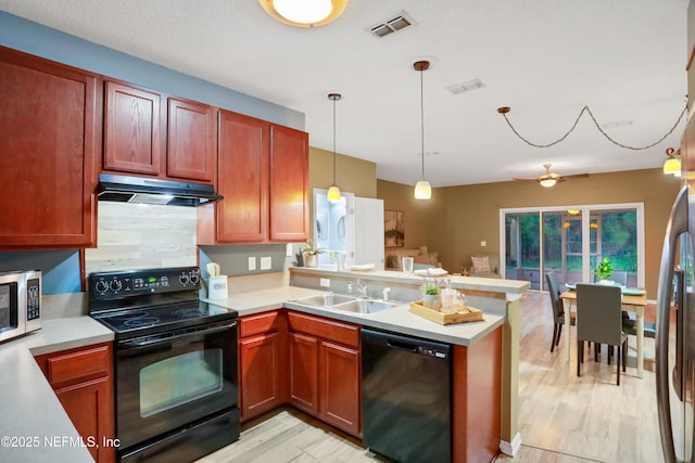 kitchen with decorative light fixtures, black appliances, sink, kitchen peninsula, and light hardwood / wood-style flooring