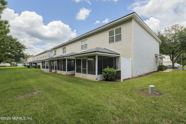 back of property with a sunroom and a lawn